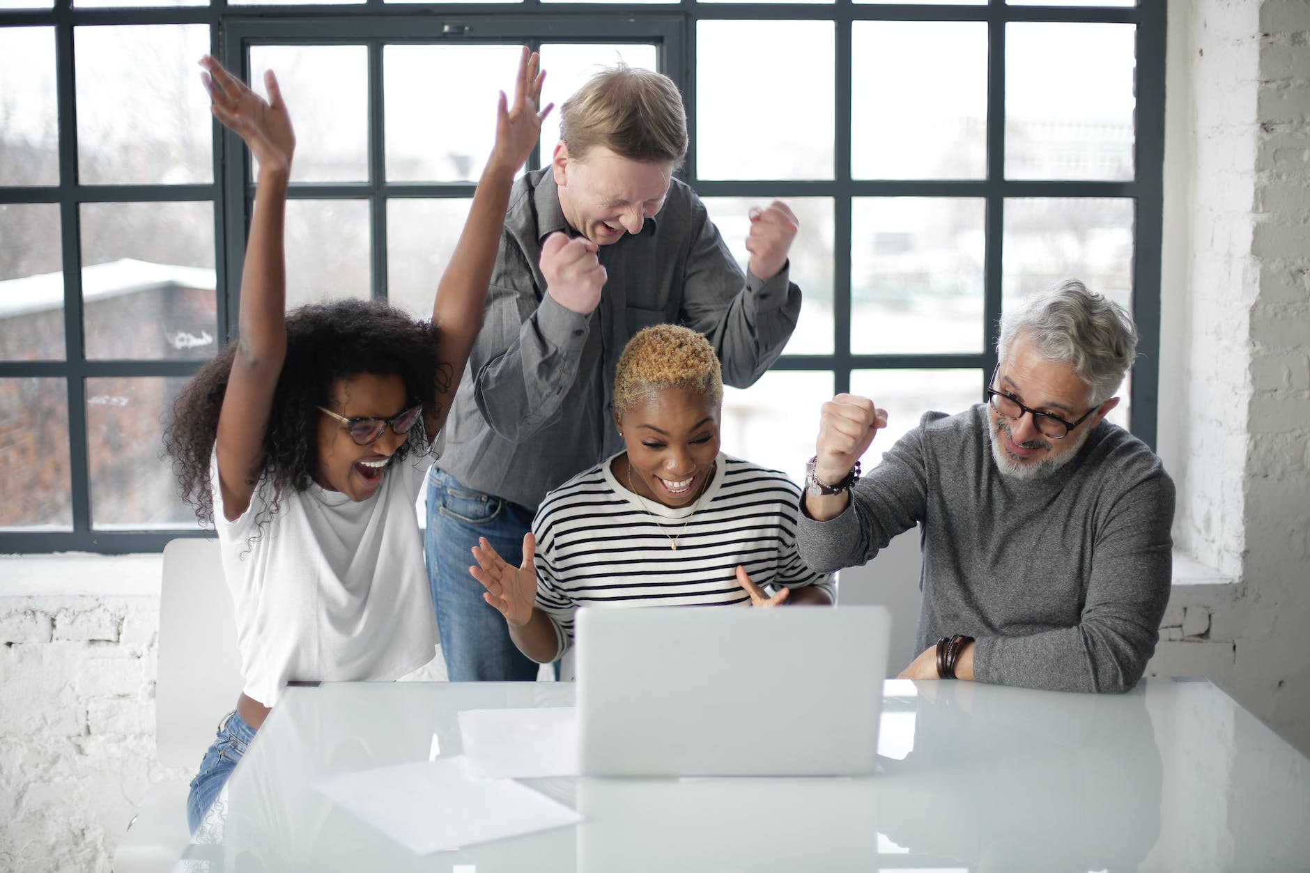 pexels-photo-3931634 excited multiracial colleagues enjoying triumph together in front of laptop in office