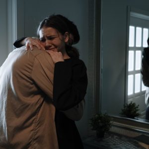 an emotional woman crying while hugging another person